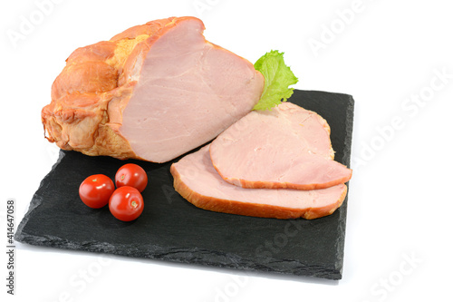 Sliced smoked pork loin with tomatoes and mustard seeds on a stone plate, isolated on a white background.