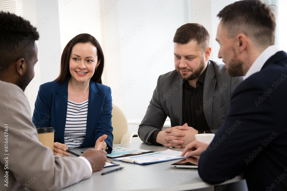 Group of business people sitting around the office desk and discussing the project Group of business people sitting around the office desk and discussing the project