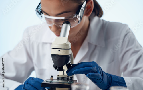 woman doctor in a medical gown and a microscope on the table glasses on the face laboratory research