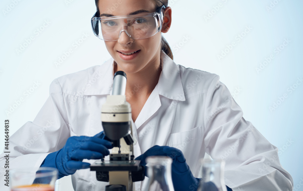 woman doctor in a medical gown and a microscope on the table glasses on the face laboratory research woman doctor in a medical gown and a microscope on the table glasses on the face laboratory research