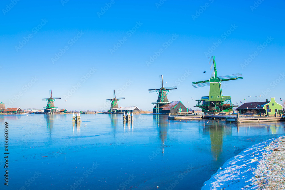 Winter beautiful Dutch houses, old windmills, frozen water in canals and rivers.