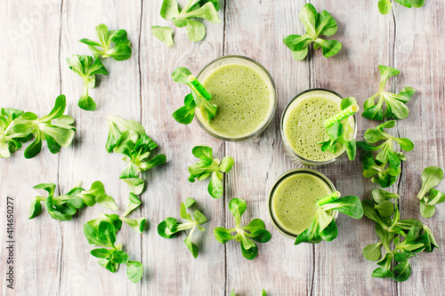 Detox diet concept: Green spinach smoothie on white wooden table