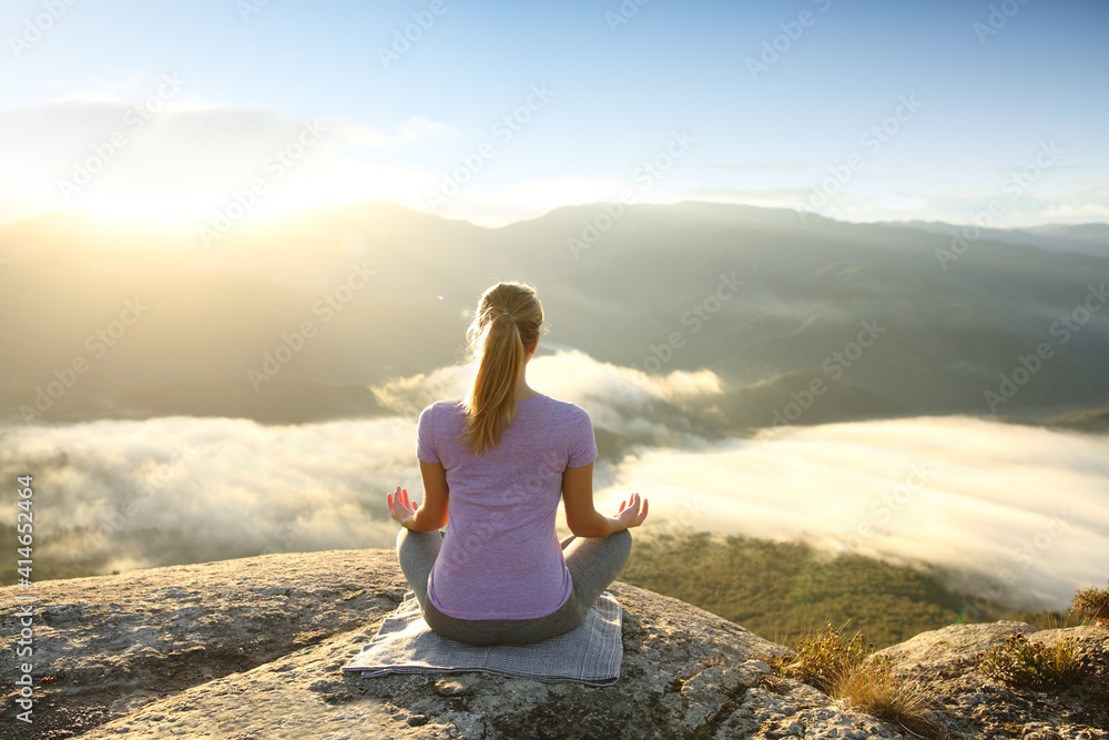 Woman in the top of a cliff meditating doing yoga