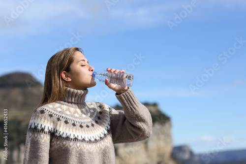 Fotografía Woman drinking water from bottle in winter in the mountain