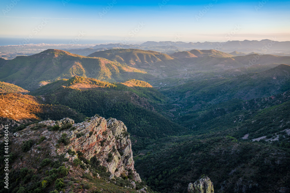 Green, hilly and rocky landscape at evening seen from above. Mediterranean landscape in Eastern Spain.