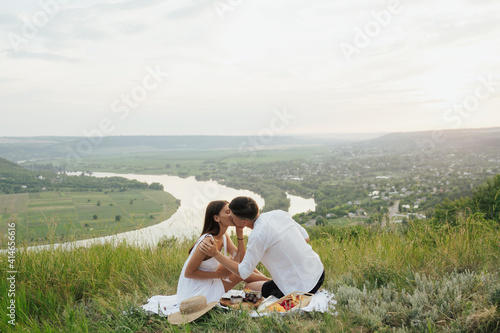 Obraz na płótnie Happy young couple kissing and having picnic outdoors on summer day. w salonie
