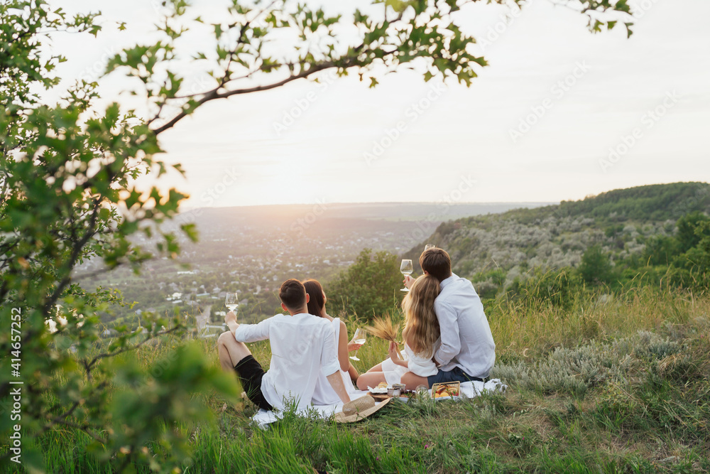 The company of gorgeous couples having fun, drink wine, and enjoy hill landscape at the summer picnic. The company of gorgeous couples having fun, drink wine, and enjoy hill landscape at the summer picnic.