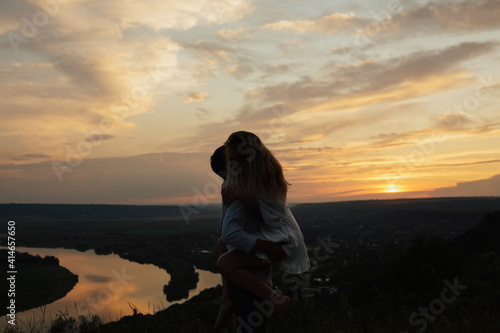 Silhouette of passionate couple with gorgeous sunset sky on background. Couple is kissing and hugging. © eduard
