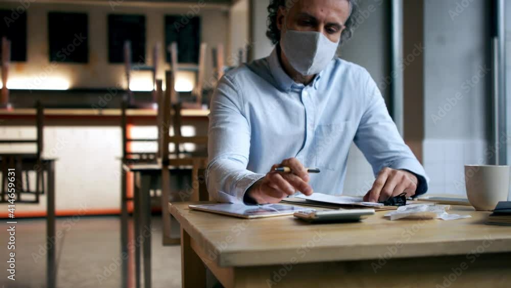 Frustrated owner calculating in closed cafe, small business lockdown due to coronavirus. Frustrated owner calculating in closed cafe, small business lockdown due to coronavirus.