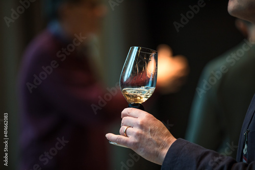 Obraz na plátne Close up on a hand holding a glass of white wine