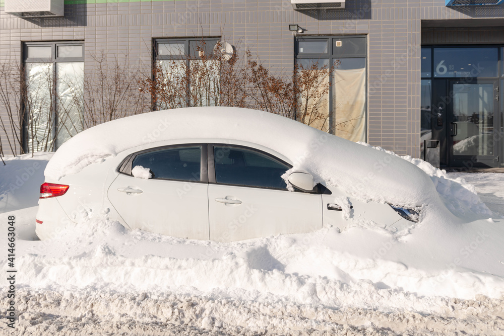 Moscow. Russia. Snowfall in February. Car in a snowdrift. After a heavy snowfall, the car was covered with snow from all sides. To leave you will have to work with a shovel