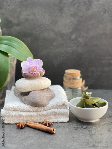 healthy lifestyle. spa style. stones on towels  orchid  aloe vera and extract  cinnamon on a gray background