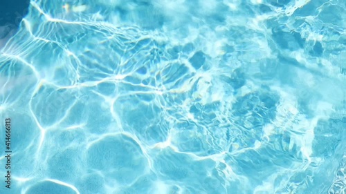 beautiful dramatic scenic bright vibrant blue clear water of pool ripples with warm sun shining light reflection on water surface on bright warm summer day. Holiday travel spa resort concept
