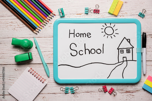 School supplies for homeschool laid out on a white wooden table with a white board with the words Home School written on it photo