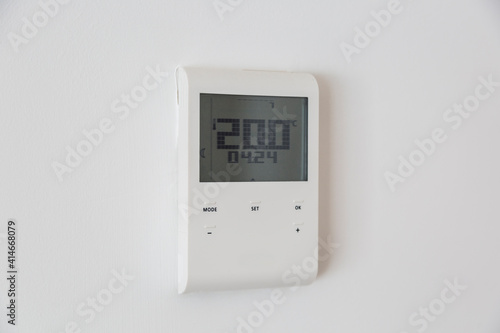 white remote temperature regulator on wall marking twenty degrees