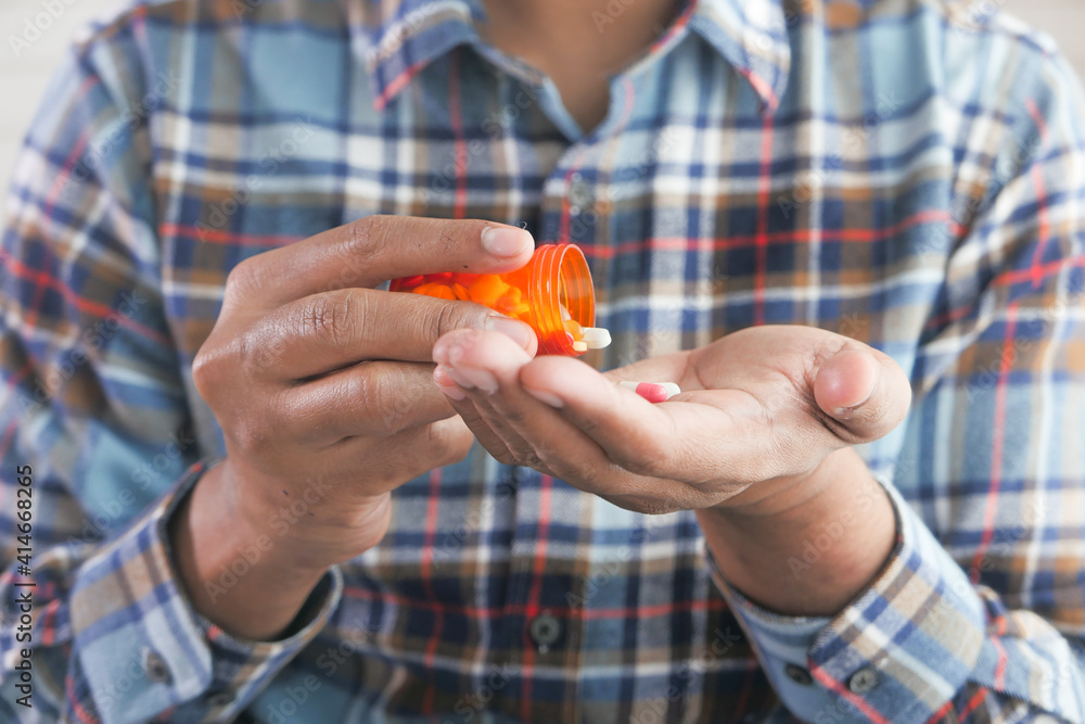 man's hand with medicine spilled out of the pill container man's hand with medicine spilled out of the pill container