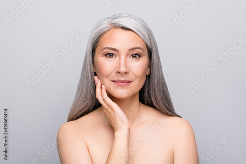 Portrait of attractive gray-haired lady touching sensitive pure fresh skin isolated over grey pastel color background
