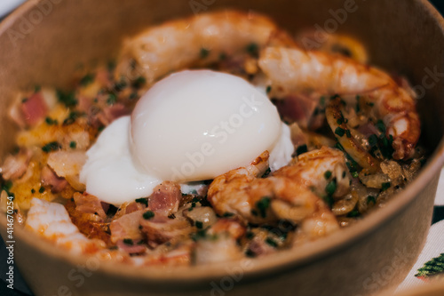Closeup shot of a dish with undercooked egg with prawns and bacon photo