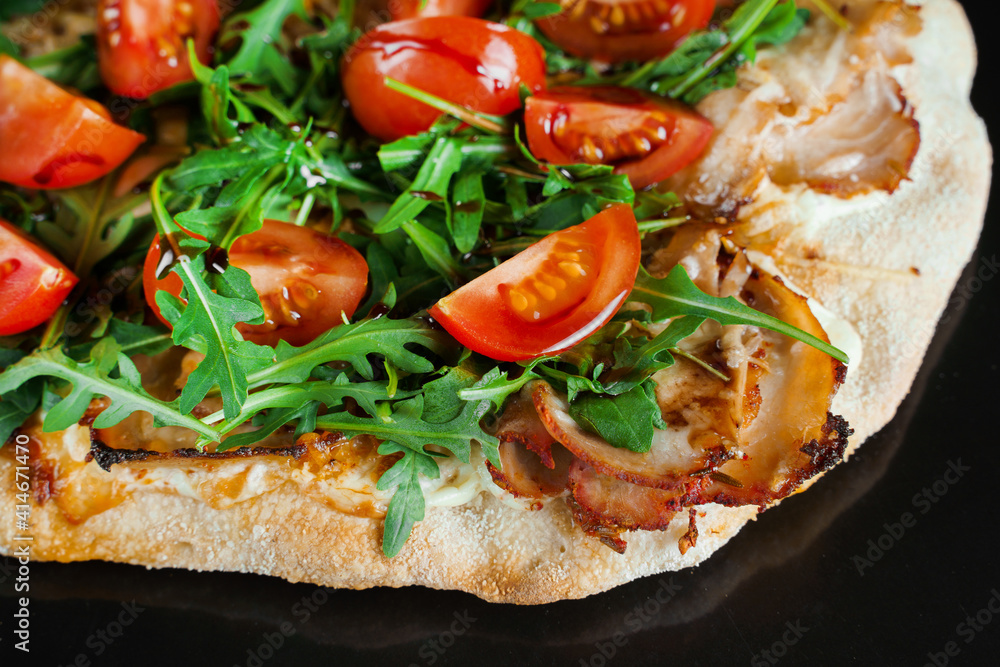 Pinsa romana gourmet italian cuisine on black background. Scrocchiarella traditional dish. Food delivery from pizzeria. Pinsa with meat, arugula, tomatoes, cheese. Pinsa romana gourmet italian cuisine on black background. Scrocchiarella traditional dish. Food delivery from pizzeria. Pinsa with meat, arugula, tomatoes, cheese.