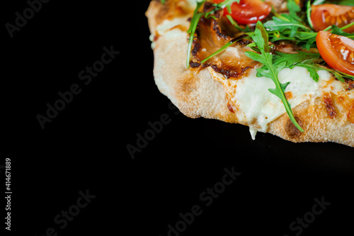 Pinsa romana gourmet italian cuisine on black background. Scrocchiarella traditional dish. Food delivery from pizzeria. Pinsa with meat, arugula, tomatoes, cheese. photo