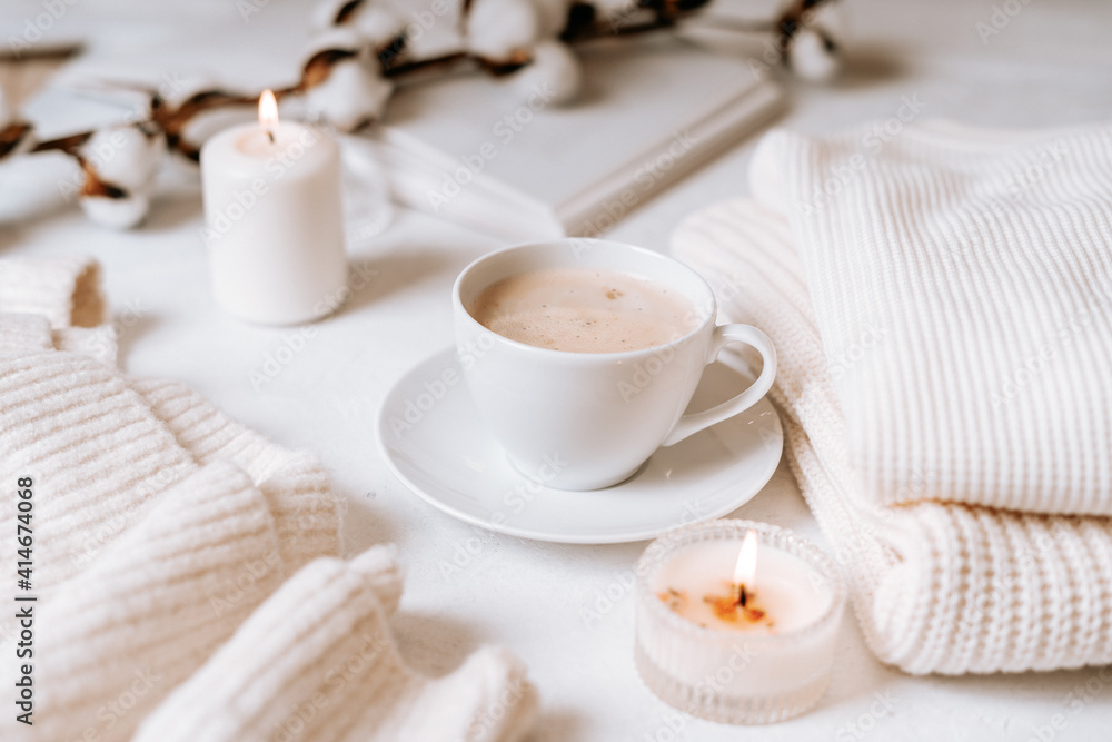 Details of still life in the home interior of living room. Cup of coffee, cotton, book, candle, sweater. Moody. Cosy autumn winter concept on white background. Decoration.