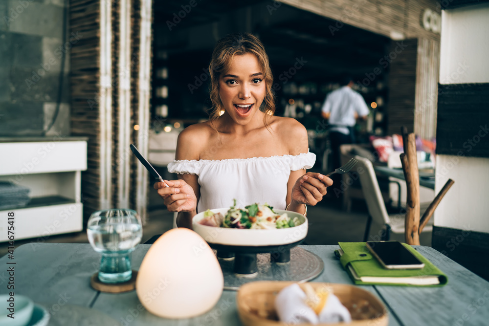 Amazed woman enjoying delicious salad in cozy cafe