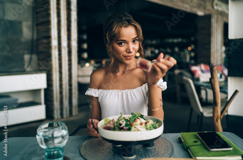 Smiling lady offering delicious salad while sitting in cafe