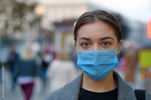 Young woman in protective mask on a crowded street look at the camera