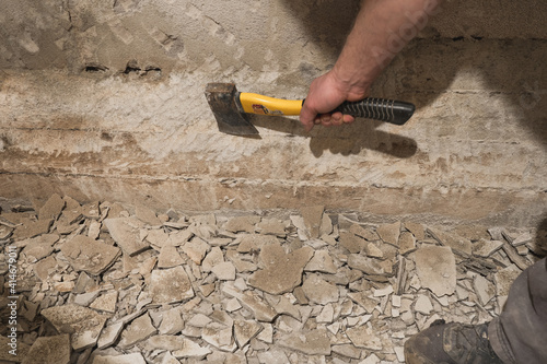 A builder using an axe to remove walls plaster.