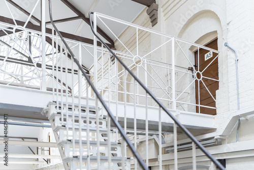 Old Victorian prison landing wing with bars and staircase of high security  immigration detention centre with brown cell door in England bright daylight