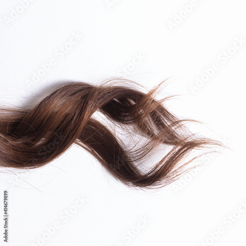 a lock of natural brunette hair on a white background