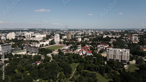 Aerial drone view of Chisinau at sunset. Panorama view of multiple buildings in city center, roads with moving cars, central park with bare trees. Moldova photo