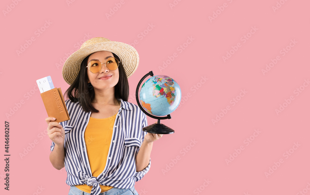 Fototapeta premium Asian woman holding passport with boarding pass and globe