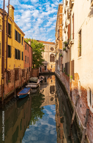 View of quiet street and narrow canal with boats along brink. The residential area of Venice, Italy.