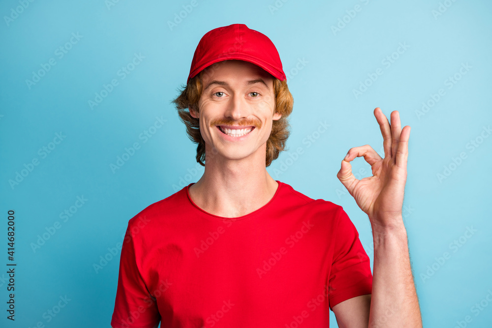 Portrait of positive person fingers show okey approval symbol wear hat have good mood isolated on blue color background Portrait of positive person fingers show okey approval symbol wear hat have good mood isolated on blue color background