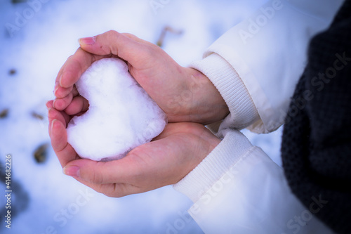 Schneeherz in den Händen halten als Symbol für Liebe im Winter trotz kalten Wintertag