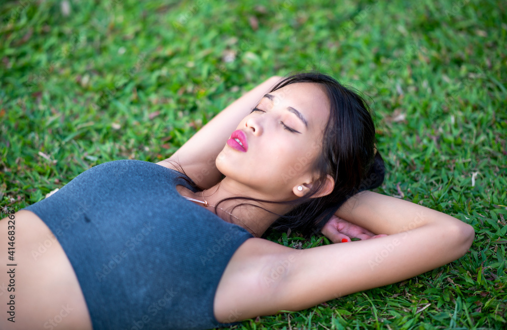 Beautiful asian girl lying down on the grass relaxing in the city park Beautiful asian girl lying down on the grass relaxing in the city park