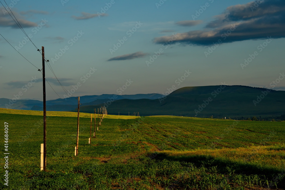 Russia. Republic of Khakassia. Illuminated by the morning sun, power transmission poles in the endless steppes.