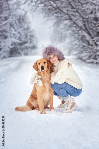 beautiful girl with golden retriever dog in snowing forest