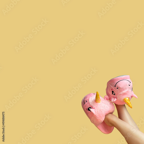 beautiful legs of a young girl in slippers unicorns on a yellow background