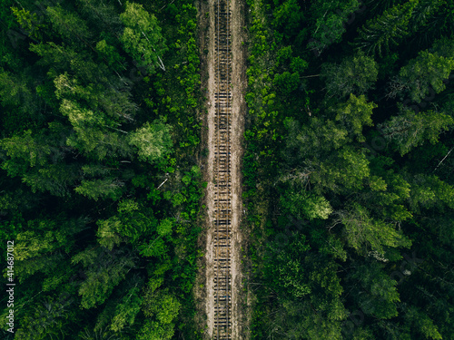Aerial view of empty railway track through green forest in Finland