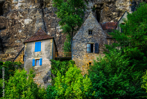 Casas de piedra con llamativas ventanas, incrustadas en la roca y entre la vegetación photo