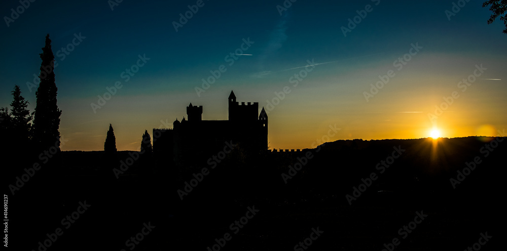 Castillo medieval francés recortándose al atardecer sobre el cielo dorado y azul