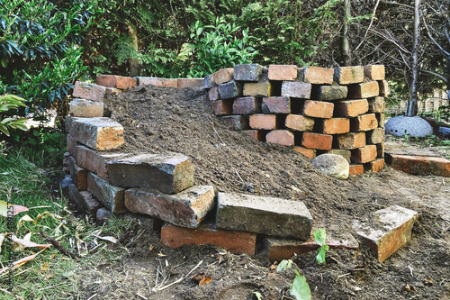 herb spiral in garden made of bricks filled with garden soil