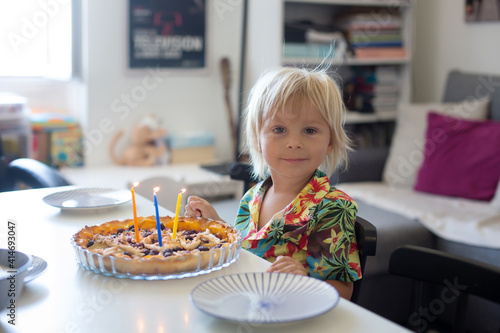 Blond toddler child, boy, celebrating his third birthday with cake at home