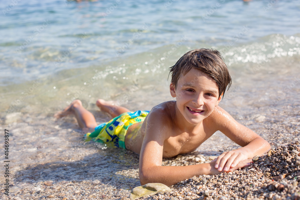 Sweet child, preteen boy, lying on the beach in France on sunset Sweet child, preteen boy, lying on the beach in France on sunset