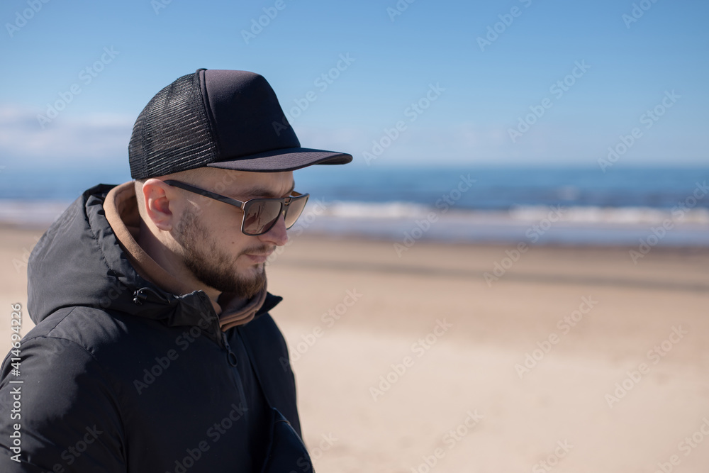Young bearded man walking on the beach.