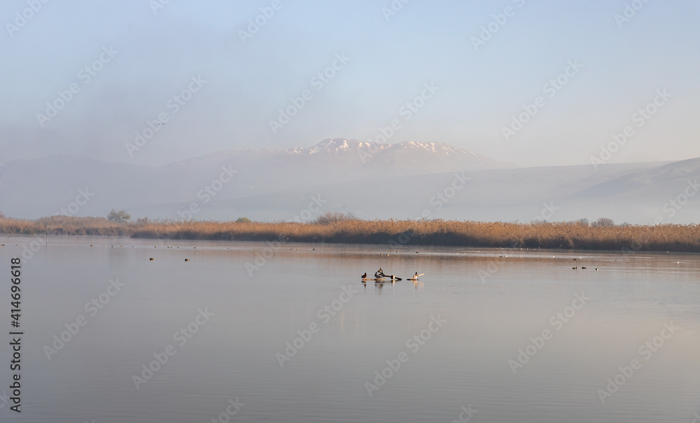 Lake  Hula against the background of the snow-capped peak of Mount Hermon on a foggy early winter morning in the nature reserve at Lake Hula in northern Israel