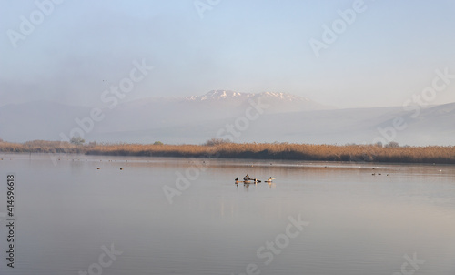 Lake Hula against the background of the snow-capped peak of Mount Hermon on a foggy early winter morning in the nature reserve at Lake Hula in northern Israel