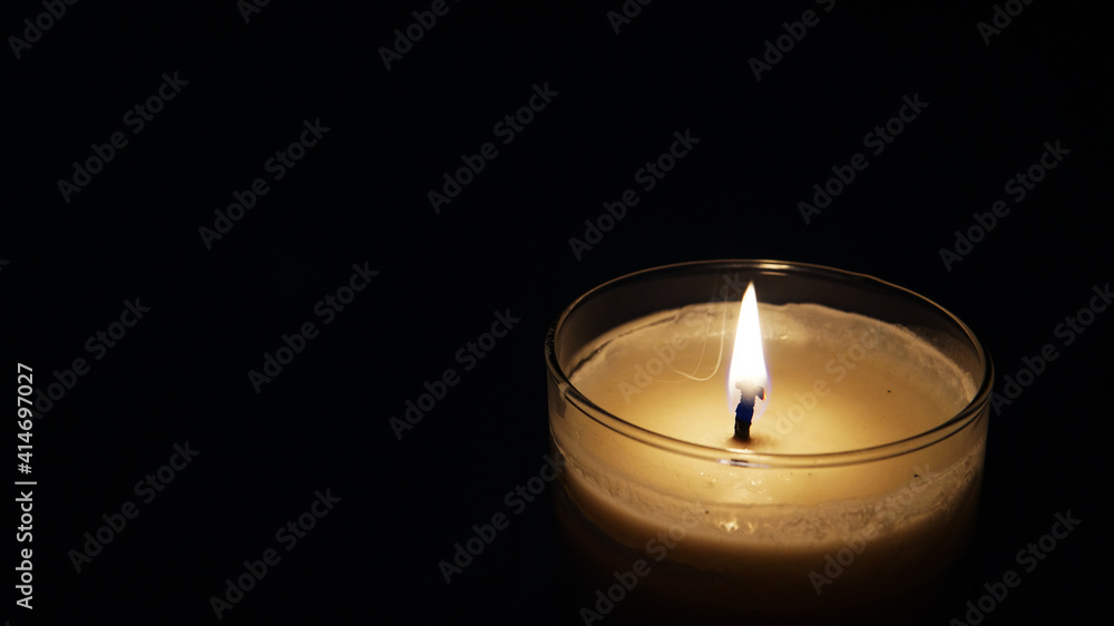 close view of lit candle over a black background close view of lit candle over a black background